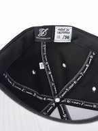 Black corduroy fitted Yofi hat with white embroidery, numbered label view